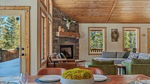 Un salon chaleureux avec une cheminée en pierre, un plafond en bois et de grandes fenêtres.