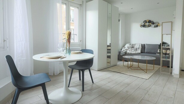 A modern living room with a sofa, a coffee table, and a dining area with chairs and a table. - Studio 2P Roland Garros/Parc des Princes (Boulogne-Billancourt)