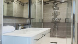 A modern bathroom with a glass-enclosed shower, a white sink, and a mirror above the sink. - Studio 2P Roland Garros/Parc des Princes (Boulogne-Billancourt)