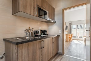 A modern kitchen with wooden cabinets, a stainless steel sink, and a microwave. - Cosy Studio -AC- 4P- Geneva (Genève)