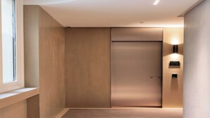 Un ascenseur moderne avec une finition métallique, un luminaire fixé au mur et un petit écran numérique.