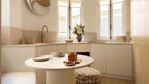 Une cuisine moderne avec une table à manger ronde, des meubles blancs, un four encastré et une fenêtre offrant une belle vue.
