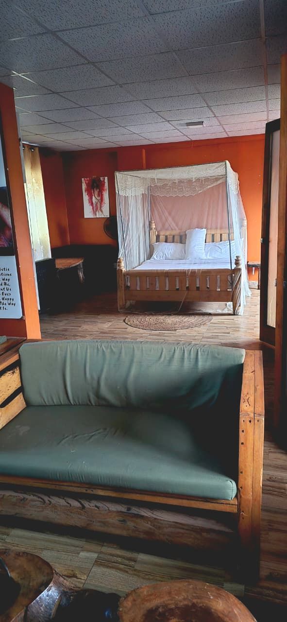 Una habitación con una cama de madera, un sofá verde y suelo de madera.