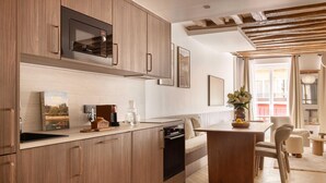 Una cocina moderna con armarios de madera, microondas integrado y un comedor con mesa y sillas de madera.