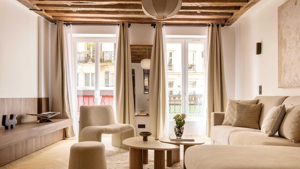 Una sala de estar moderna con techo de madera, un sofá, una mesa de centro y un banco.