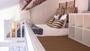 Habitación infantil con una cama litera, una cuna blanca y un mueble de almacenamiento blanco.