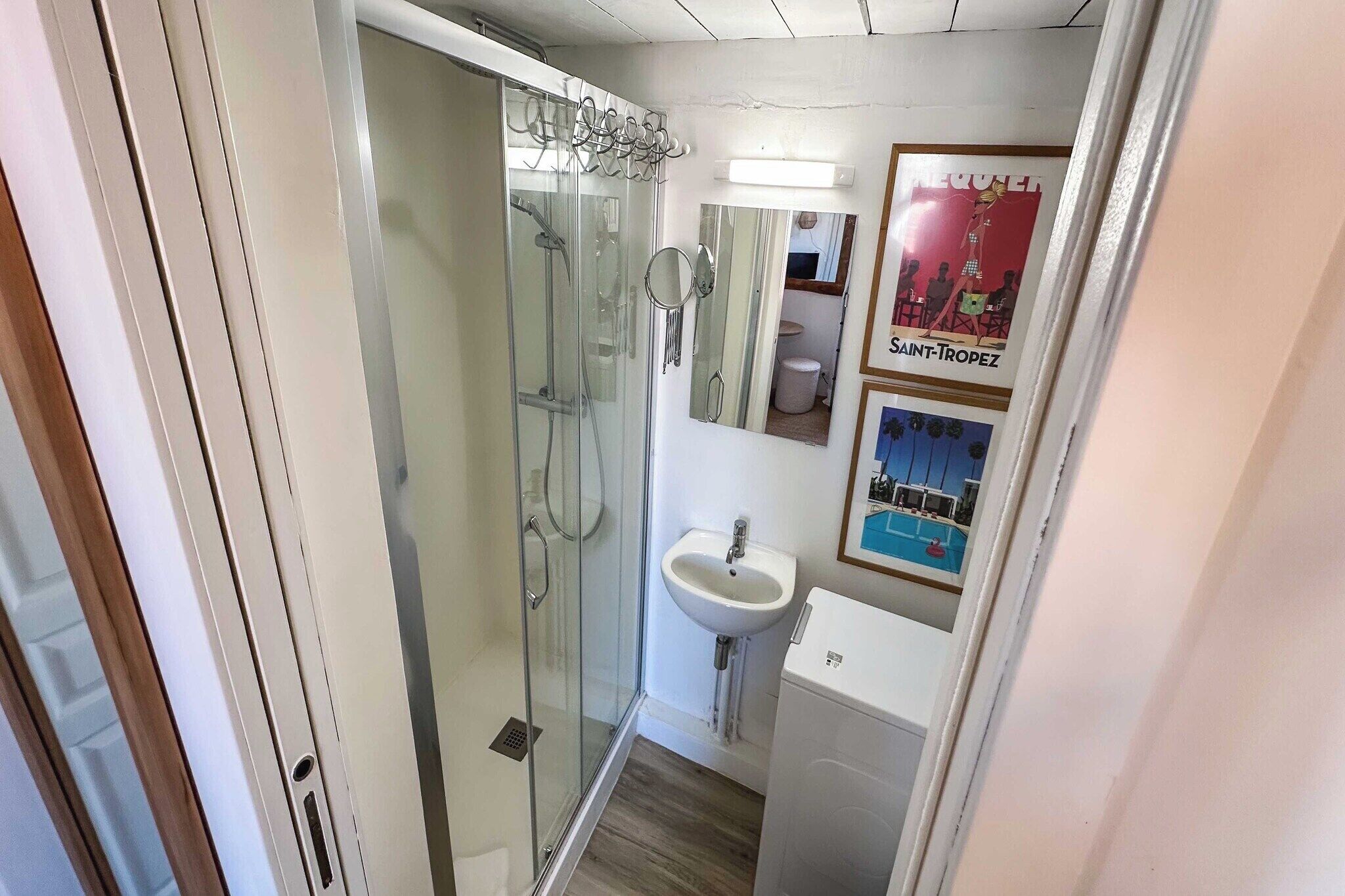 A compact bathroom with a glass-enclosed shower, a sink, and a mirror.