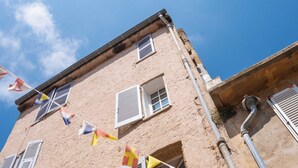 Un edificio con varias ventanas, algunas con contraventanas, y un equipo de aire acondicionado visible.