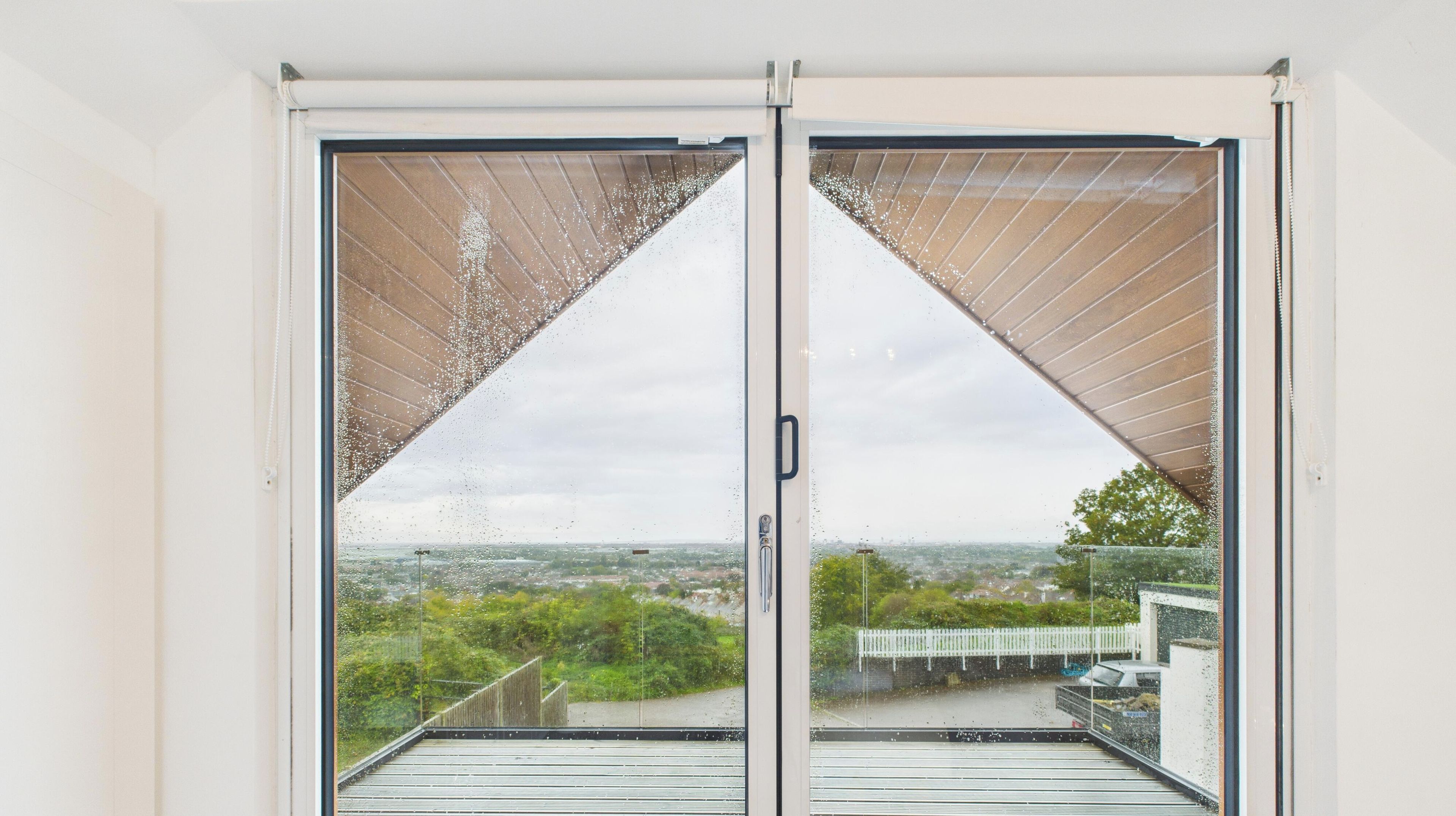 A view through a glass door with a metal frame, leading to a balcony with a metal railing.