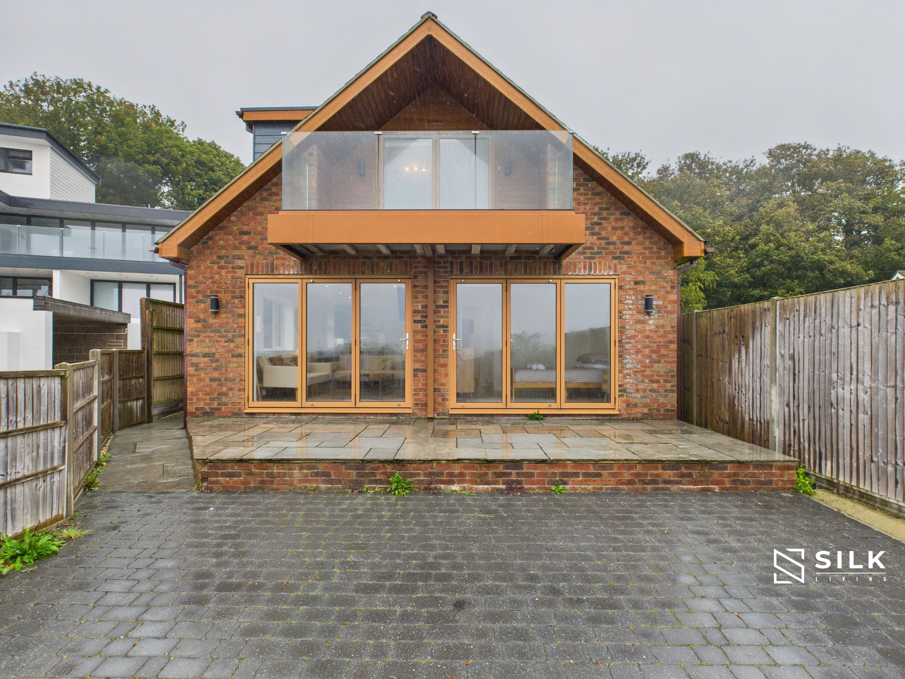 A modern house with a brick facade, large sliding glass doors, and a sloped roof.