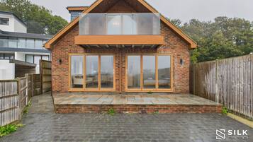 A modern house with a brick facade, large sliding glass doors, and a sloped roof.