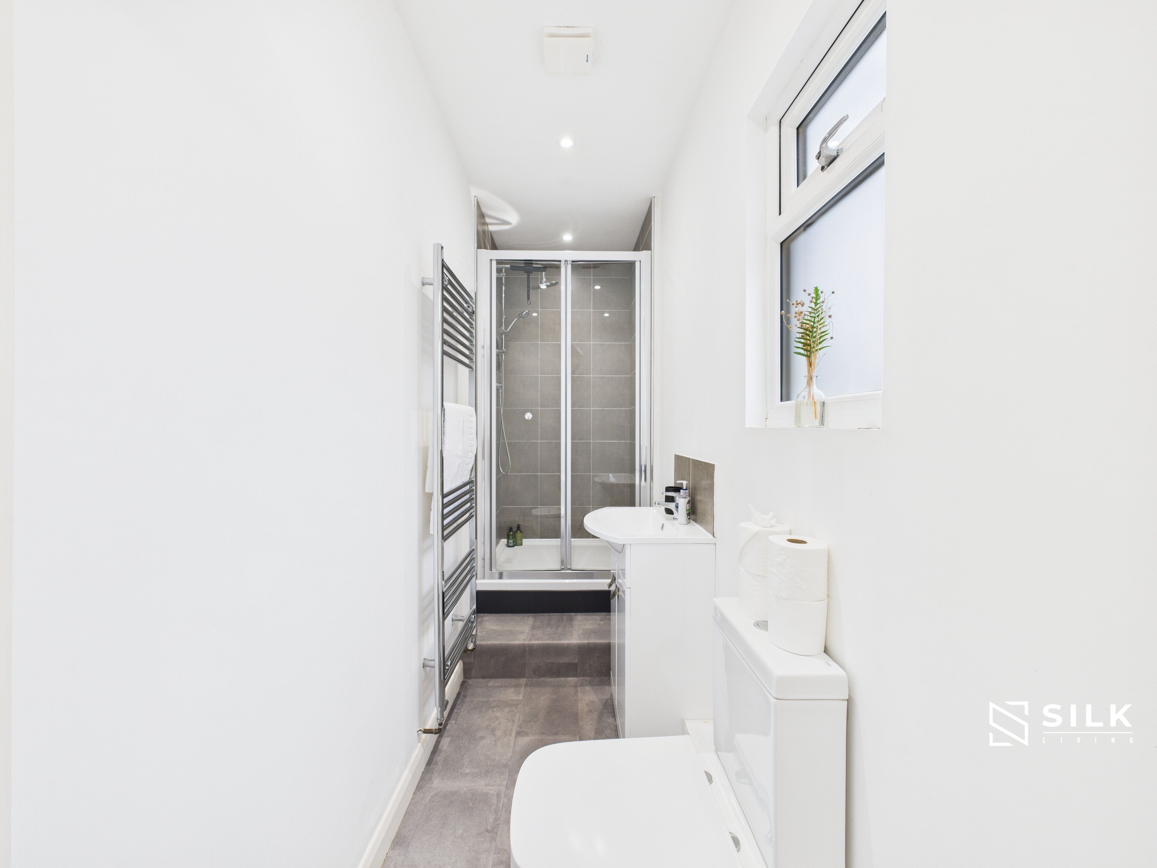 A modern bathroom with a glass-enclosed shower, a white sink, and a toilet.