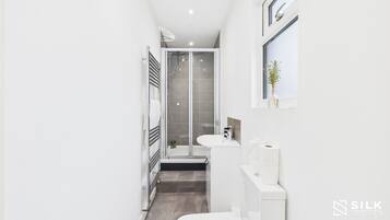 A modern bathroom with a glass-enclosed shower, a white sink, and a toilet.
