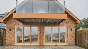 A house with a brick exterior, large sliding glass doors, and a covered patio area.