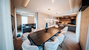 Een moderne eethoek met een lange houten tafel, comfortabele stoelen en hanglampen.