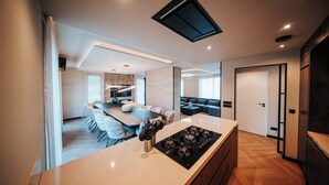 Een moderne keuken met een centraal eiland, een eethoek met witte stoelen en een inbouwoven.