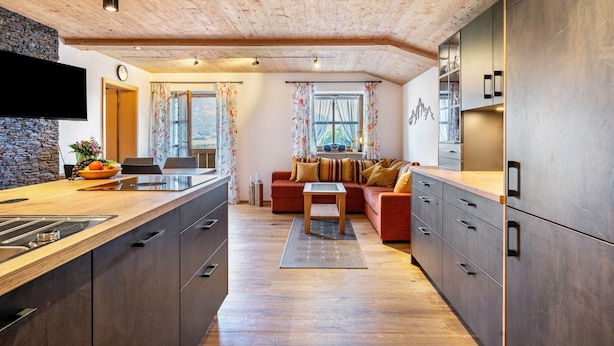 Une cuisine moderne avec des meubles en bois, une cuisinière encastrée et un grand îlot central doté d’un évier.