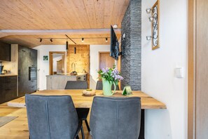 Eine moderne Küche mit Holzausstattung, eine Essecke mit Holztisch und -stühlen sowie eine Wand mit Steinakzenten.