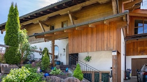 Un bâtiment en bois doté d’un balcon, d’un escalier et d’une voiture garée à l’extérieur.
