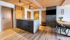 Une cuisine moderne dotée d’un îlot central, d’un plafond en bois et d’éléments décoratifs en pierre.