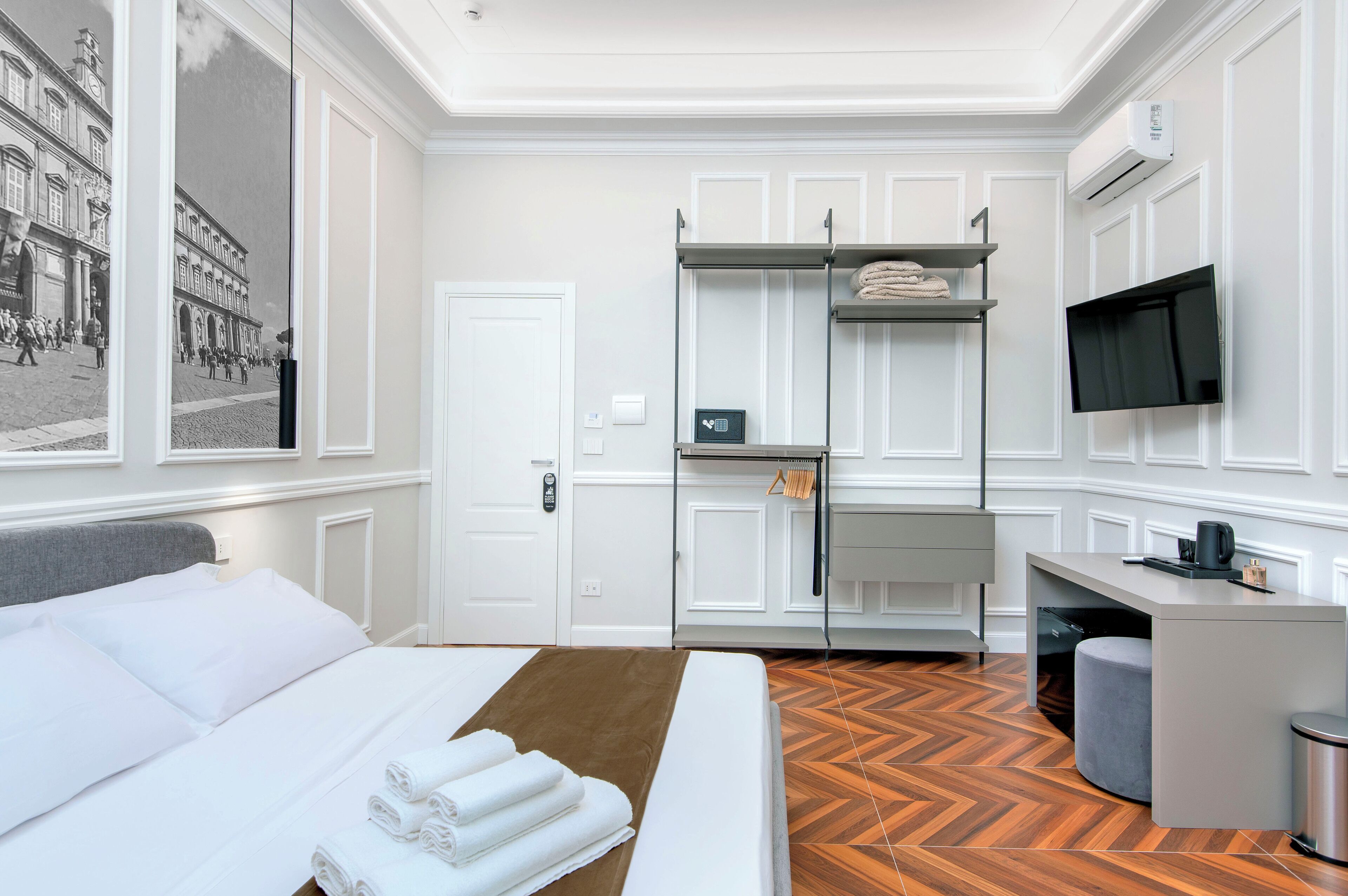 Habitación de hotel con cama, escritorio, televisor y vista a una calle a través del ventanal.