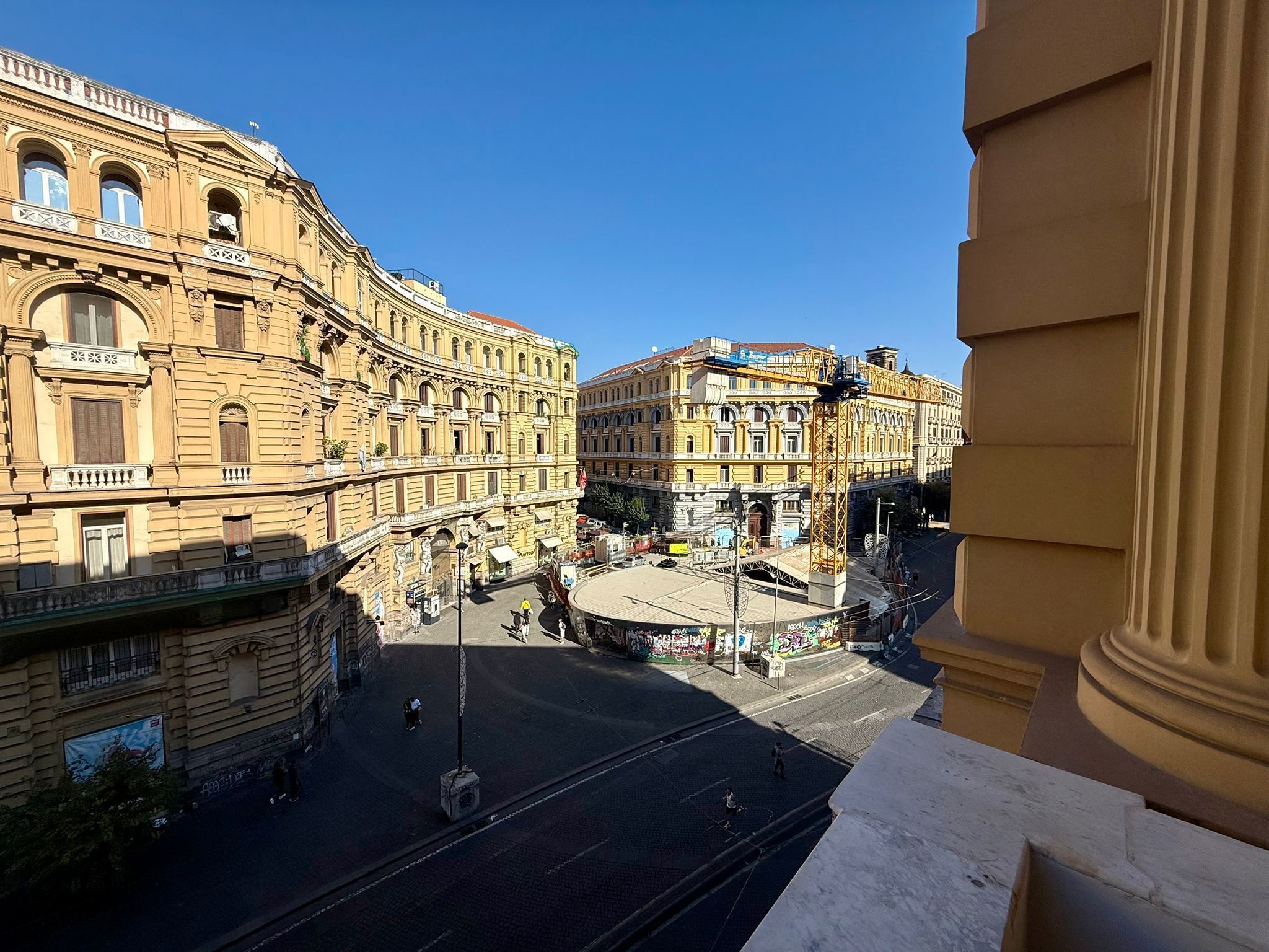 A historic building with classical architecture, a central open square, and a tram line.
