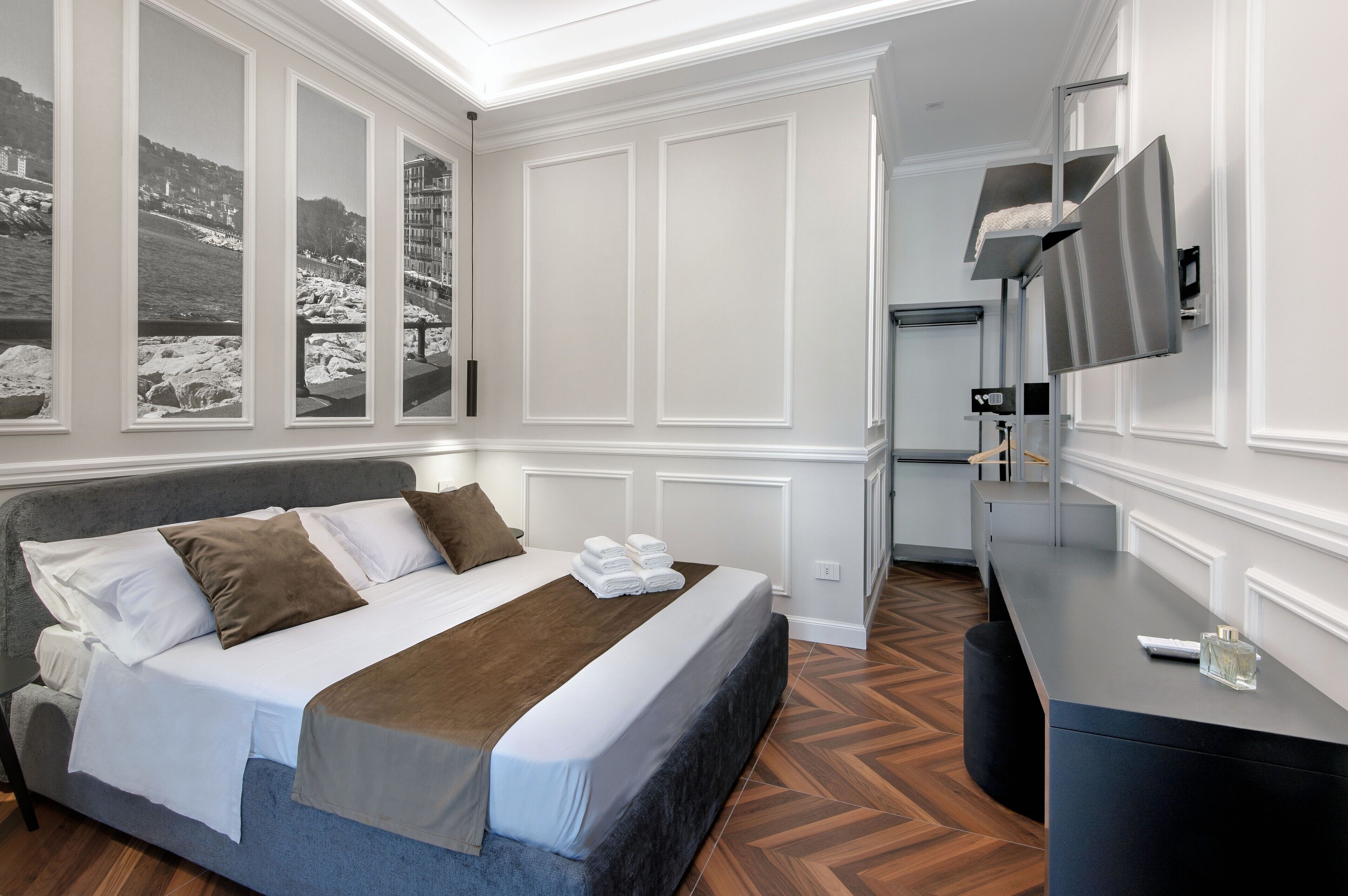 Ein modernes Hotelzimmer mit einem großen Bett, einem Schreibtisch mit Flachbildfernseher und Blick auf eine verschneite Landschaft durch die Fenster.