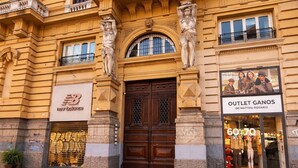 A historic building with a large central entrance, two visible storefronts, and a cobblestone ground. - Naples Plaza Duomo (Naples)