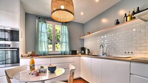 Una cocina moderna con armarios blancos, una mesa de comedor redonda y una lámpara colgante.