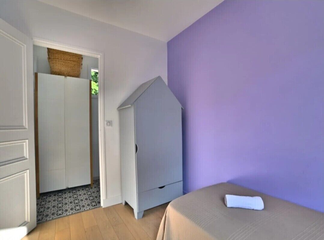 Quarto com cama, guarda-roupa e parede roxa.