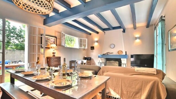 Un comedor con una mesa de madera dispuesta para una comida, un sofá y un televisor al fondo.