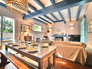 Un coin repas avec une table en bois dressée pour le repas, un canapé et un téléviseur en arrière-plan.