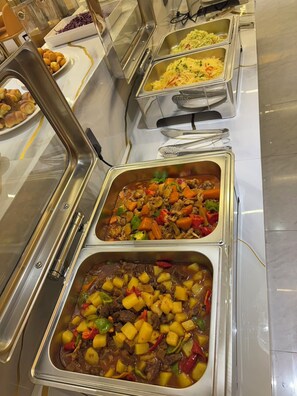 A buffet with various dishes including pasta, meat with vegetables, and other prepared foods. - Crystal Hotel (Bishkek)