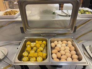 A buffet with trays of corn and eggs. - Crystal Hotel (Bishkek)