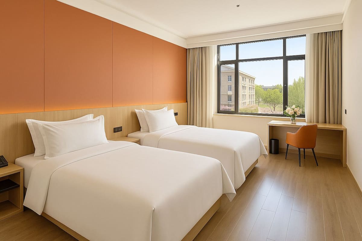 A hotel room with two beds, a desk, and a chair.