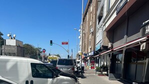 Una calle con coches aparcados y un edificio con un letrero que dice 'JOI Suites'.