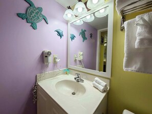 Un baño con lavamanos, espejo, toallero y adornos en la pared.