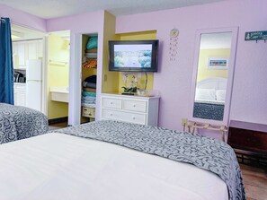 Un dormitorio con cama, televisor, armario y espejo.