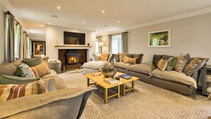Ein gemütliches Wohnzimmer mit Kamin, bequemen Sofas, einem Couchtisch und einem Fernseher.