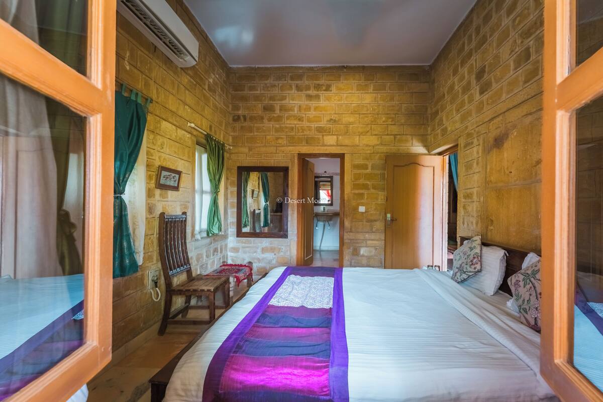 A room with a large bed, wooden walls, a wooden bench, and a small table.