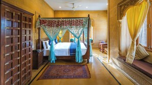 Um quarto espaçoso com cama de dossel, armário de madeira e uma janela grande com cortinas.