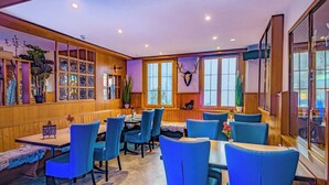 Un restaurante con paredes revestidas de madera, sillas tapizadas en azul y una variedad de platos decorativos en la pared.
