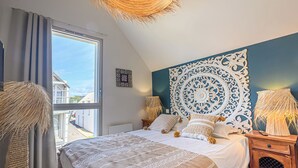 A bedroom with a large bed, a decorative headboard, a window with curtains, and a view of the outside.