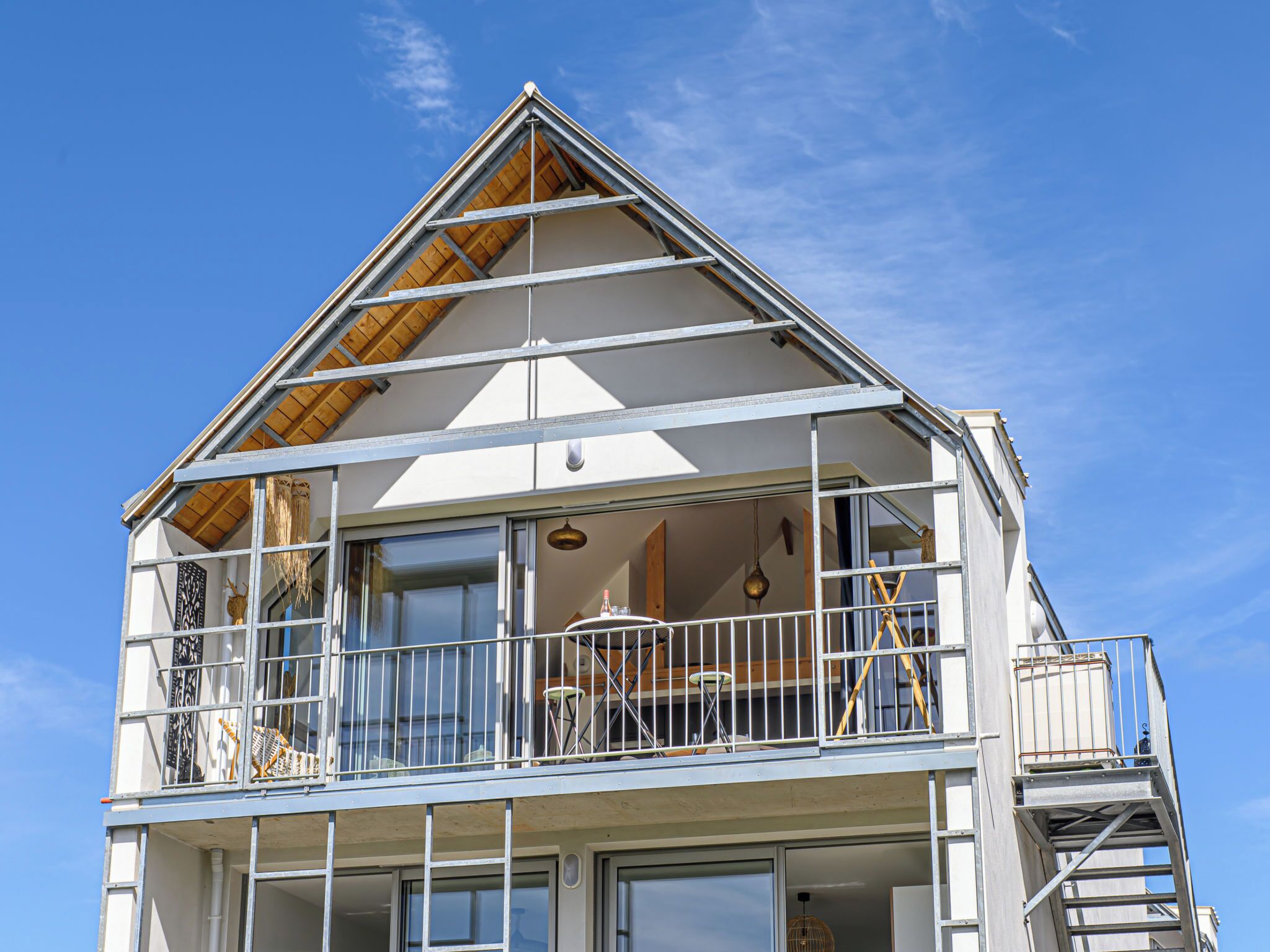 A two-story building with a balcony on the upper floor, large windows, and a wooden roof.
