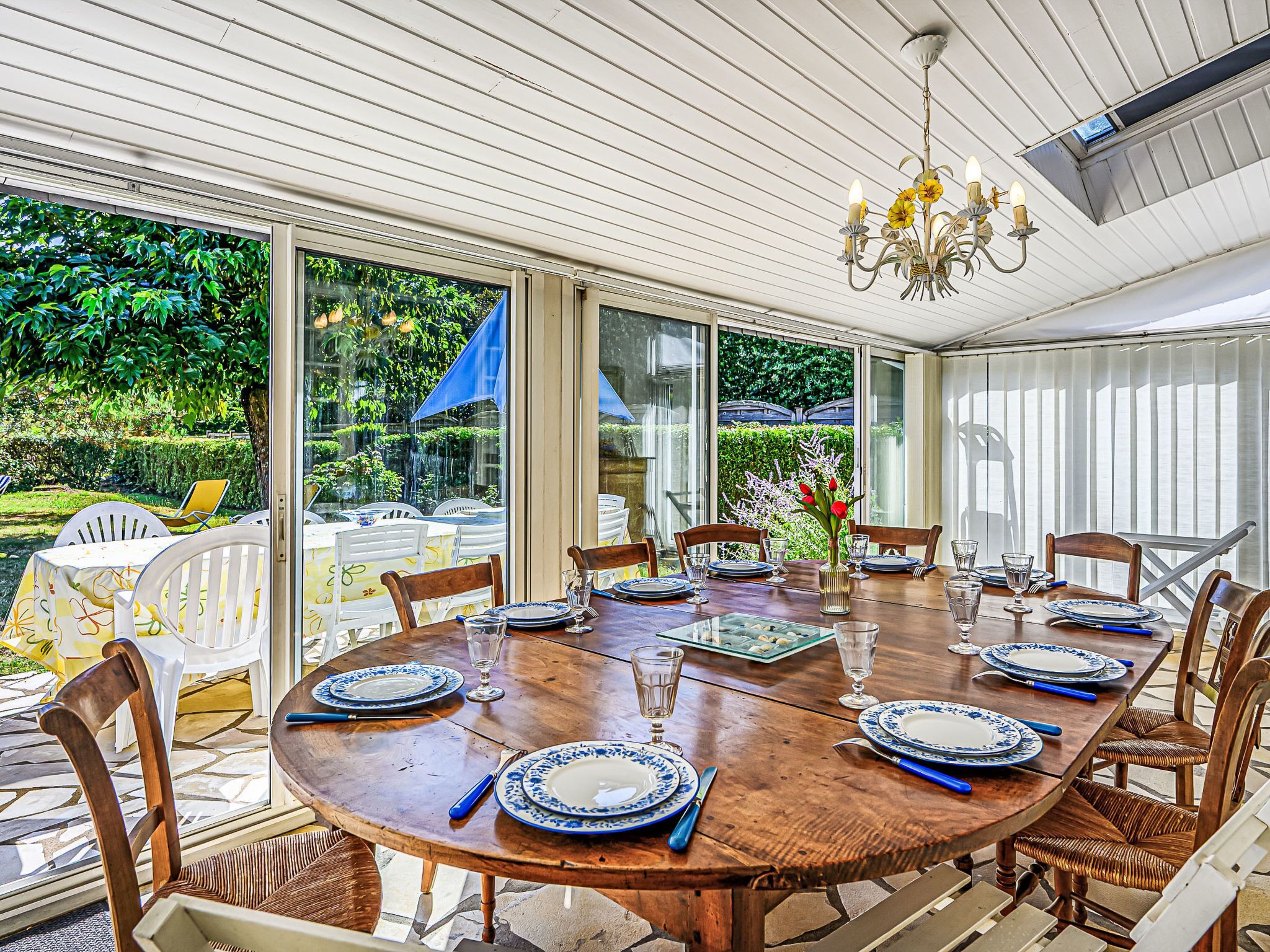 A dining area with a round wooden table set for six, surrounded by wicker chairs.