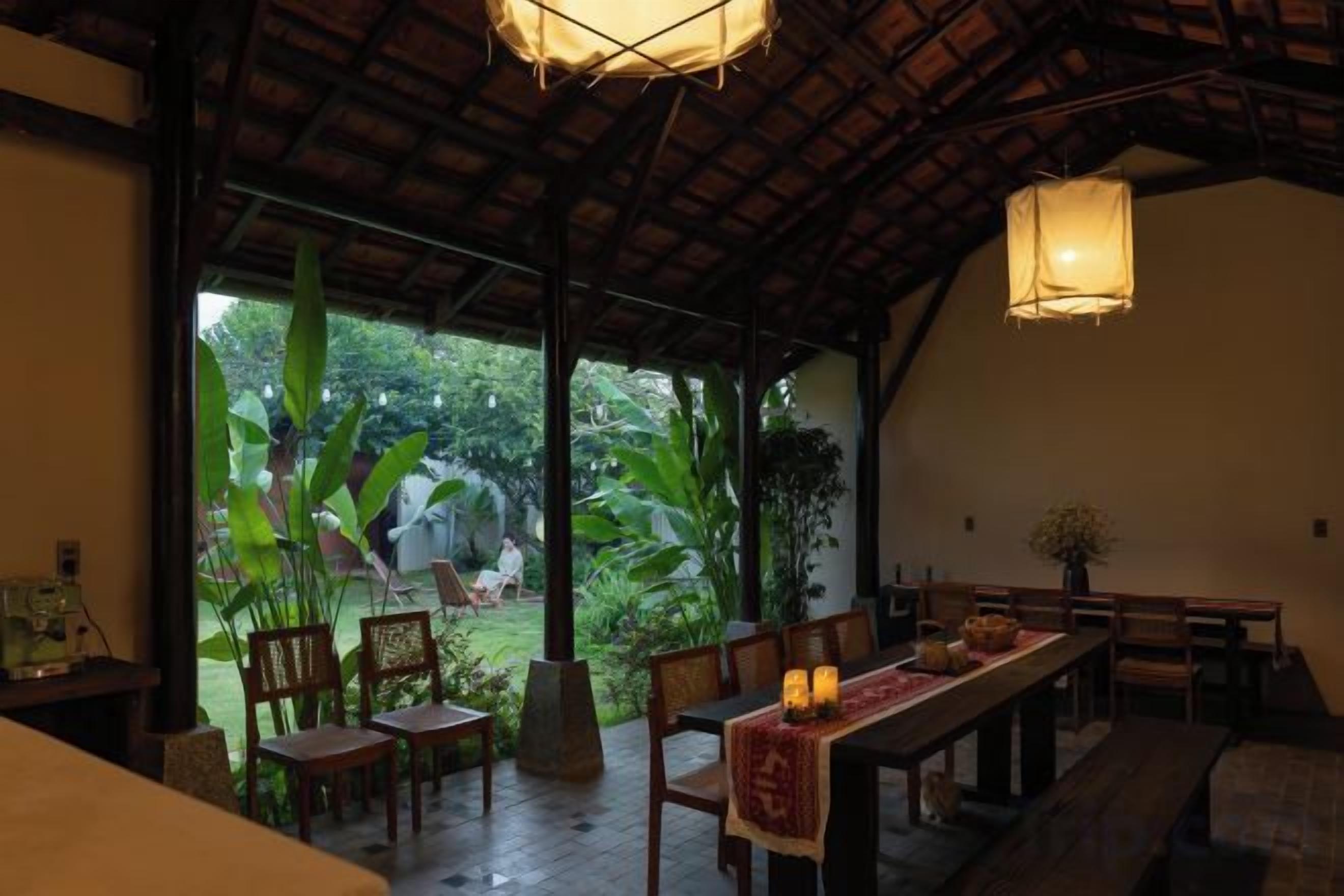 Un comedor interior con techo de madera, amplios ventanales y vistas al exterior con vegetación.