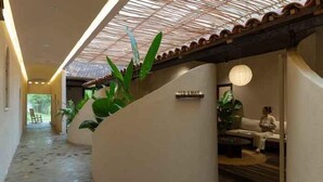 A hallway with a tiled floor, a cat walking, and a seating area with a sofa and a table.