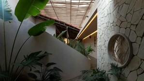 A staircase with a textured wall, a circular decorative element, and lush indoor plants.