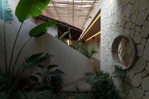 A staircase with a textured wall, a circular decorative element, and lush indoor plants. - Moonlight Homestay & Garden (P. Thong Nhat)