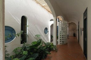 A corridor with arched windows, a tiled floor, and a white wall. - Moonlight Homestay & Garden (P. Thong Nhat)
